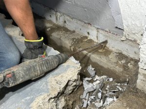 Basement Waterproofing in Martinsville technician drilling weep holes to relieve hydrostatic pressure in foundation wall